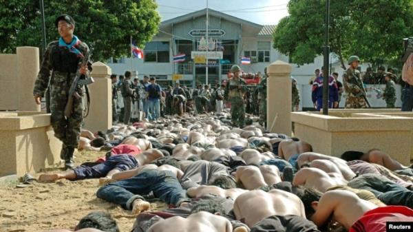 FILE - 泰国士兵走过2004年10月25日在曼谷以南约1150公里的泰国那拉提瓦省泰拜市警察局外与警察发生冲突后被逮捕的数百名男子。