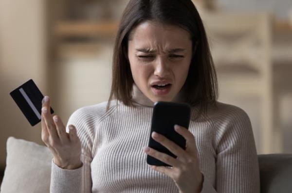 一位女性对着手机和信用卡感到沮丧