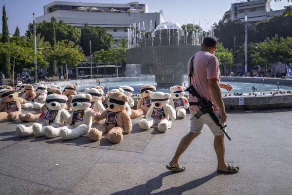 An off-duty Israeli soldier walks by an installation of blindfolded giant teddy bears adorned with photos of Israelis held captive in Gaza, in Tel Aviv, Israel. The installation is meant to draw attention to over 200 people who were abducted by Hamas militants during a bloody and unprecedented Oct. 7 cross-border attack. An off-duty Israeli soldier walks by an installation of blindfolded giant teddy bears adorned with photos of Israelis held captive in Gaza, in Tel Aviv, Israel. The installation is meant to draw attention to over 200 people who were abducted by Hamas militants during a bloody and unprecedented Oct. 7 cross-border attack.