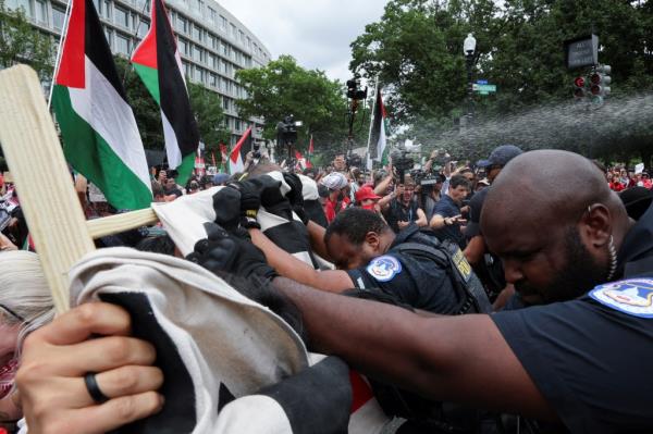 U.S. Capitol Police officers using pepper spray to control pro-Palestinian demonstrators with flags during a protest in Washington, DC while Israeli PM Netanyahu addresses Congress.