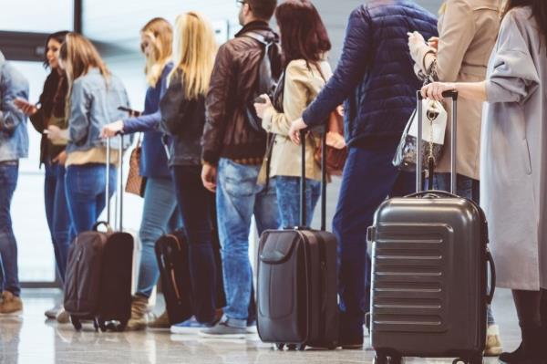 Shot of queue of passengers waiting at boarding gate at airport.