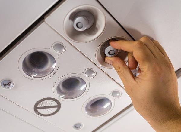 Man's hand adjusts the air vent on an airplane