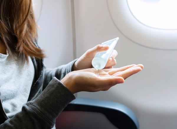 A woman uses hand sanitizer on a flight