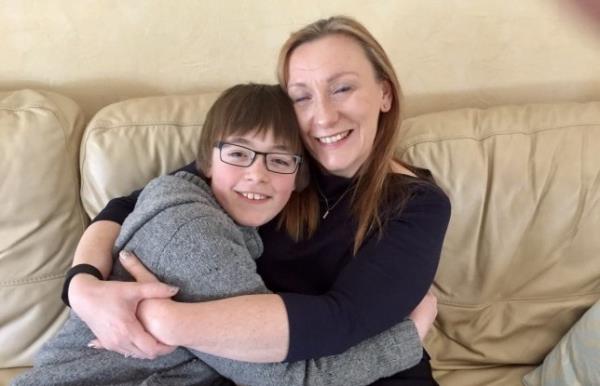 Julie Bale and her son, James, hugging each other on a sofa