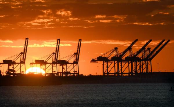cranes at the Port of Baltimore are silhouetted against the sunrise.