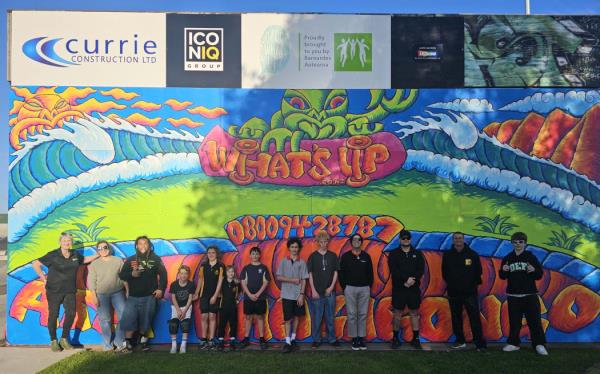 Gisborne Boys' High teachers and students with the mural designed to raise awareness of a free counselling service for young people in distress.
