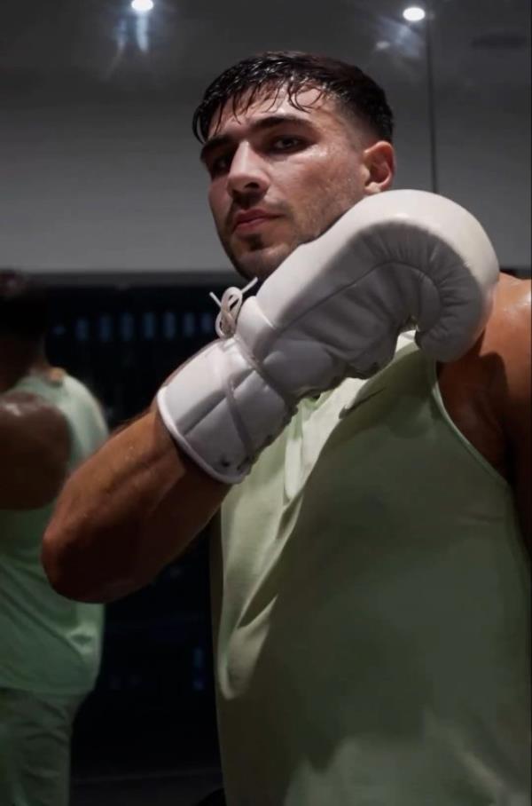 Tommy Fury poses with boxing glove held up as he breaks a sweat in training following hand surgery amid his split from Molly-Mae