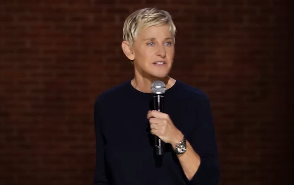 Ellen DeGeneres holding a microphone in her Netflix special For Your Approval