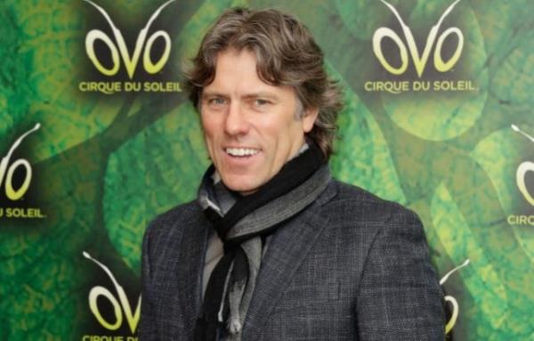 John Bishop在Cirque du Soleil OVO首映式上微笑，穿着灰色围巾和夹克