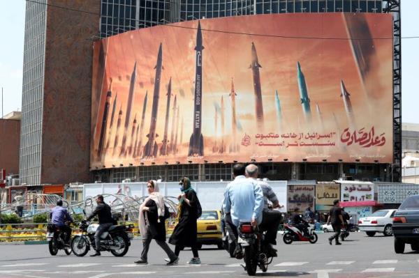 Motorists drive their vehicles past a billboard depicting Iranian missiles in Tehran on April 20, 2024, a day after Iran's state media reported explosions in the central province of Isfahan. (Photo by ATTA KENARE / AFP) Related conte