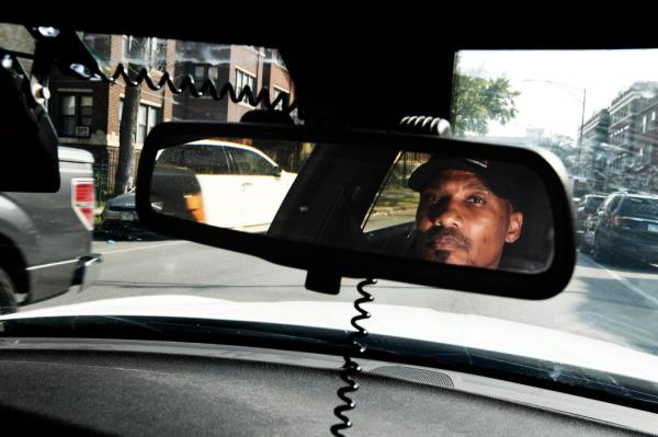 Tyrone Muhammad, a former convict turned street activist, patrolling inner city in a car, mediating between police and gangs to avoid violence.