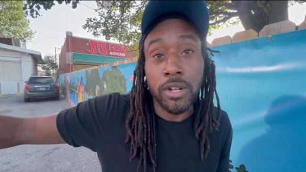 A Gangster Disciples member named David, a man with dreadlocks wearing a hat, yelling in anger about 'terrorist gangs' entering the country and Chicago illegally.