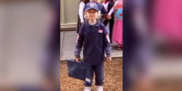 A child dressed up as a paramedic while holding on to a satchel bag.