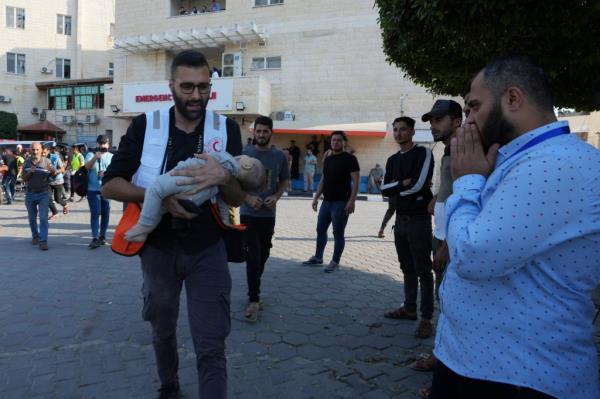 A Palestinian medic carries the body of a baby killed in Israeli airstrikes on the Gaza Strip in al-Aqsa hospital in Deir el-Balah, Gaza Strip, Saturday, Oct. 14, 2023.