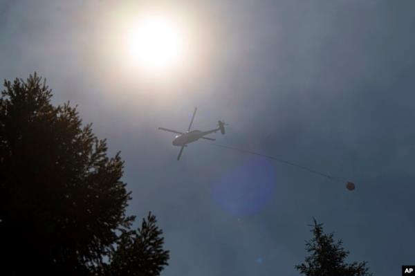A helicopter carries water over the Park Fire near Forest Ranch, California, July 30, 2024.