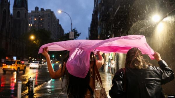 在2024年8月6日的纽约市，民众在暴风雨中用塑料雨衣保护自己。
