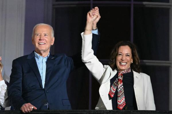 US President Joe Biden and Vice President Kamala Harris holding hands, watching the Independence Day fireworks from the Truman Balcony of the White House