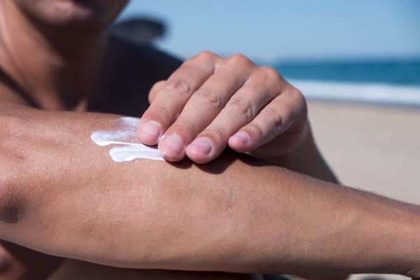 man applying sunscreen on a beach