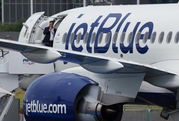 Man standing in the doorway of an airplane with JetBlue branding at Farnborough International Airshow, Britain, July 22, 2024.