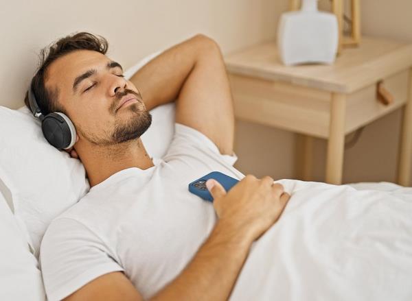 A man listening to a relaxing podcast in bed