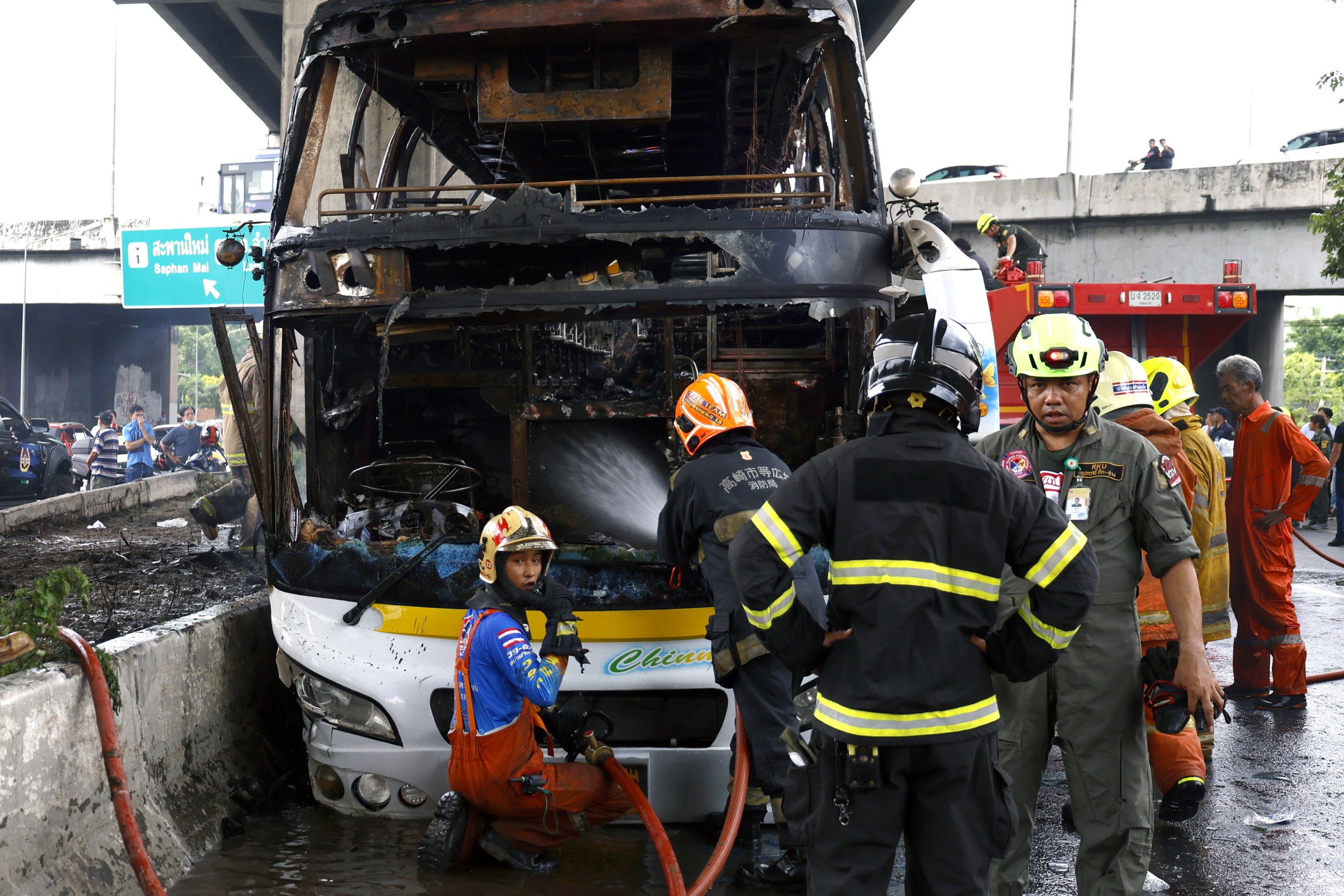 epa11634754 First response teams work in the area where a bus carrying students caught fire after a gas leak, at Vibhavadi Rangsit road in Bangkok, Thailand, 01 October 2024. At least 10 students were killed in the accident and many others were injured, police said. EPA/NARONG SANGNAK