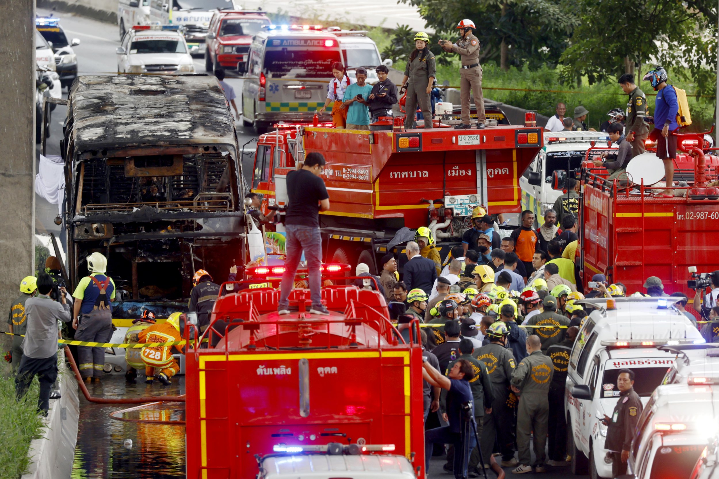 epa11634741 First response teams work in the area where a bus carrying students caught fire after a gas leak, at Vibhavadi Rangsit road in Bangkok, Thailand, 01 October 2024. At least 10 students were killed in the accident and many others were injured, police said. EPA/NARONG SANGNAK