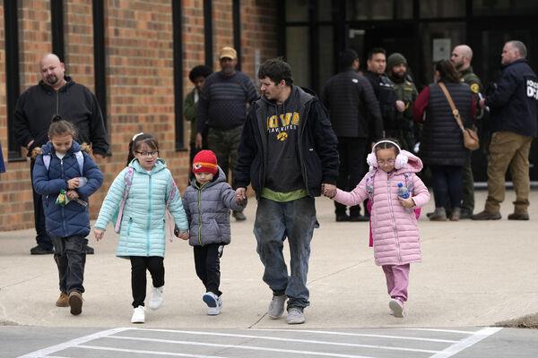 A man and children leave the McCreary Community Building after being reunited following a shooting at Perry High School. Picture: AP Photo/Charlie Neibergall A man and children leave the McCreary Community Building after being reunited following a shooting at Perry High School. Picture: AP Photo/Charlie Neibergall