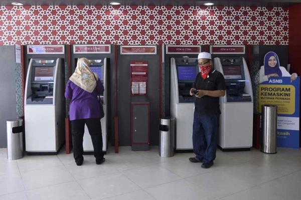 Customers use automated teller machines at a Bank Islam branch in Shah Alam on March 26, 2020. — Picture by Miera Zulyana