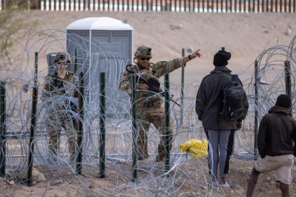 Texas National Guard troops pushing back migrants attempting to cross into the US through a wire barrier set up by the Abbott administration on March 24, 2024.