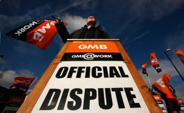 A GMB Union member holds a wooden sign at a picket line