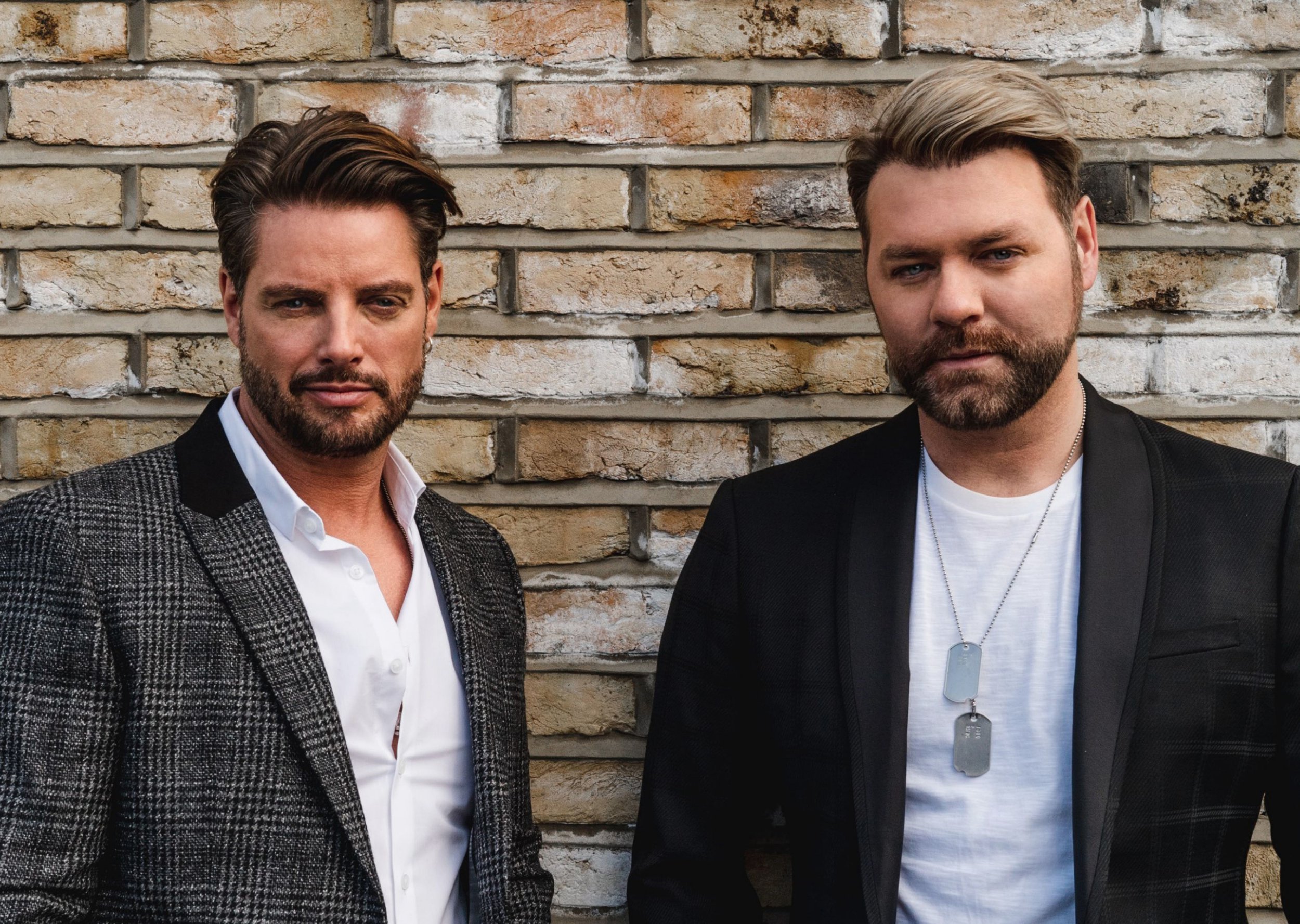 Keith Duffy and Brian McFadden of Boyzlife pose for a photo against brick wall