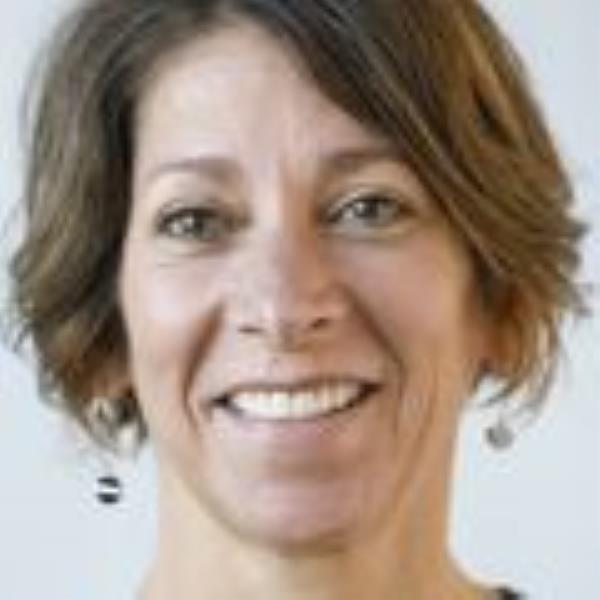 Kerri Winters-Stone, Ph.D., has short brown hair and is smiling against a light blue/gray background.