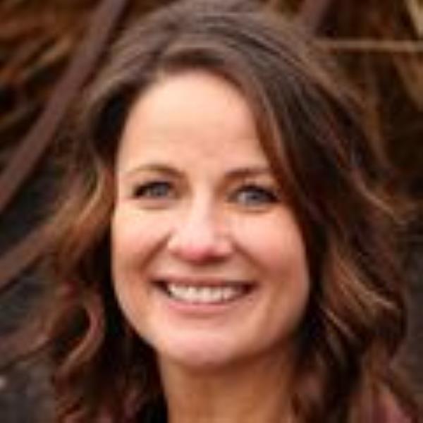 Rebecca Stricker, RN, has long, wavy brown hair, a burgundy-color top and smiling in a garden area.