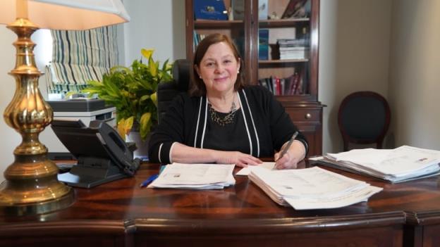 A woman sits at a desk in an office