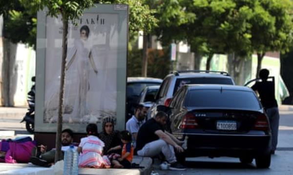 People lie and sit on the street under a fashion advert