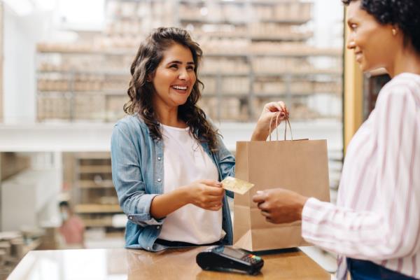 Happy young woman paying with credit card in a ceramic store