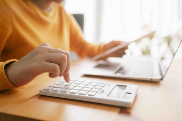 Close-up of young woman's hand using a calculator to check and calculate monthly bills at home