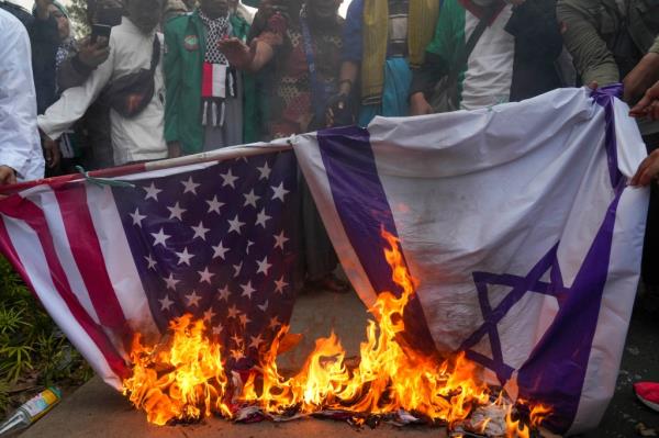 Muslim protesters burn US and Israel national flags during a rally against the Israeli airstrikes in Gaza, outside the US Embassy in Jakarta, Indonesia on Oct. 11, 2023.