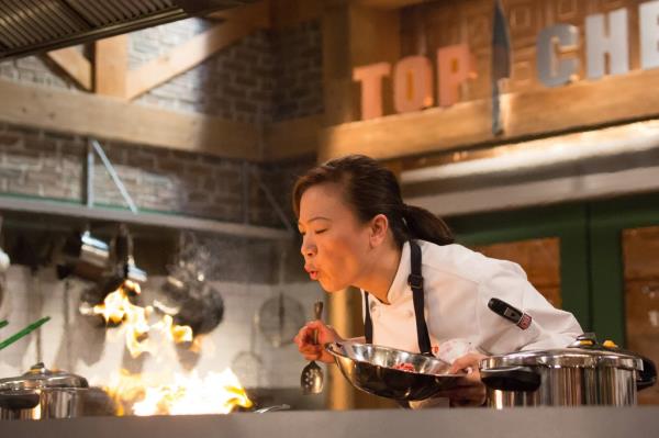 Shirley Chung, in chef's uniform, tasting from a spoon during Top Chef Season 14.