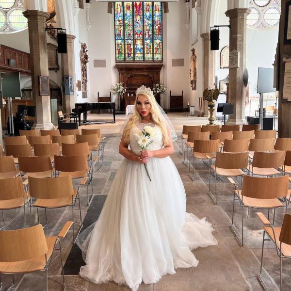 Image of Carey in a wedding dress holding a bouquet in a church.