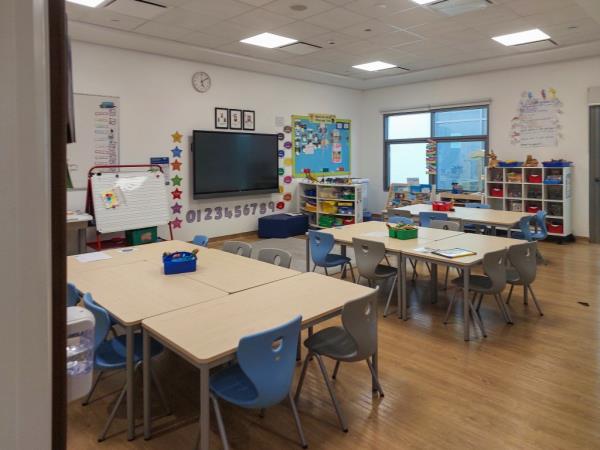 Empty daycare center classroom with chairs and tables, no children or teacher present