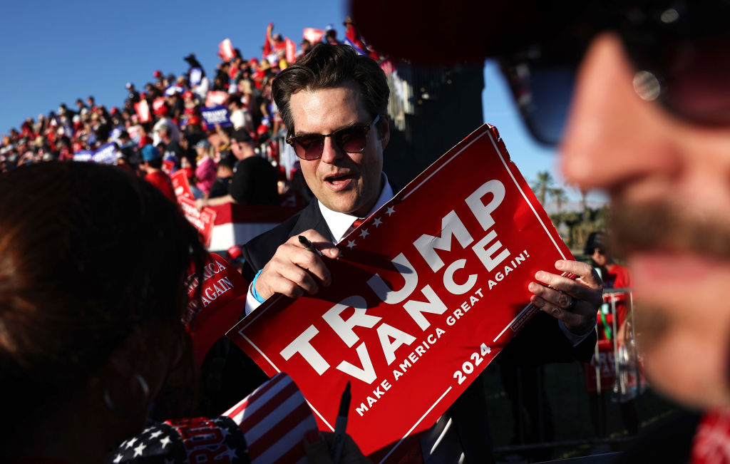 Matt Gaetz prepares to sign a Trump-Vance sign at a campaign rally for Republican presidential nominee.