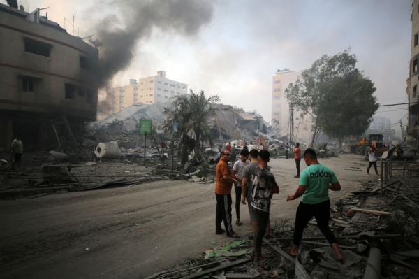 Palestinians gather next to the ruins of Watan Tower, which was destroyed in Israeli strikes, in Gaza City October 8, 2023.
