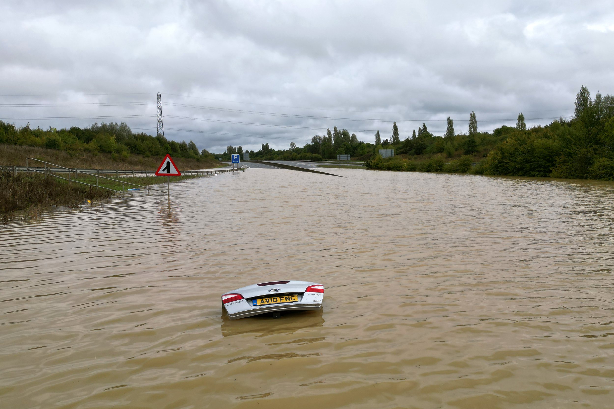 The open boot of a car is visible above the water where the vehicle is submerged in flood water on a421 in Marston Moretaine, Bedfordshire. Parts of Britain have been struck by flash floods after some areas saw more than a month's worth of rain in 24 hours. Heavy rainfall has seen parts of Northamptonshire, Bedfordshire and London submerged causing widespread travel disruption and damage to properties. Picture date: Monday September 23, 2024. PA Photo. Photo credit should read: Joe Giddens/PA Wire