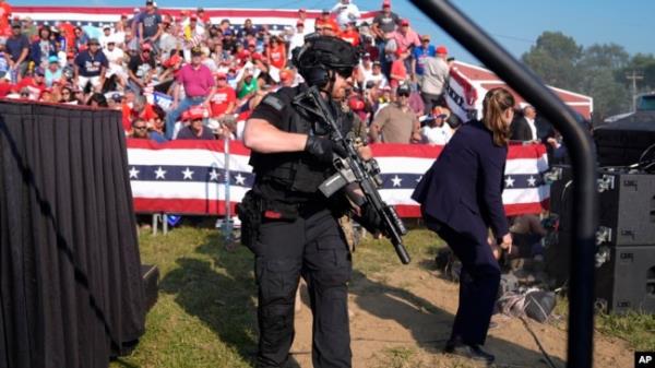 FILE - U.S. Secret Service agents surround the stage as other agents cover Republican presidential candidate former President Donald Trump at a campaign rally in Butler, Pennsylvania, July 13, 2024.