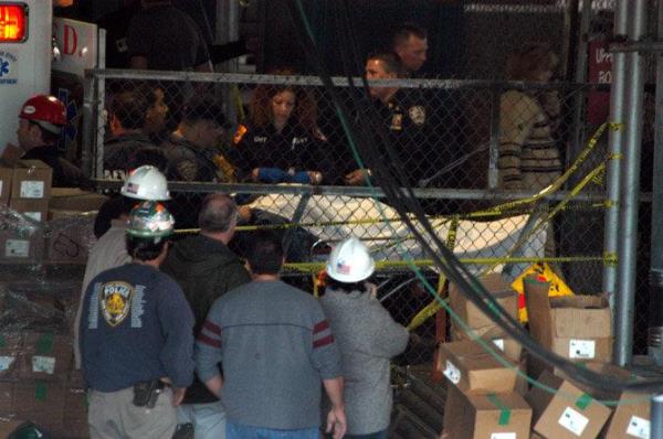 A victim is brought out from the Staten island Ferry barberi as construction workers look on.