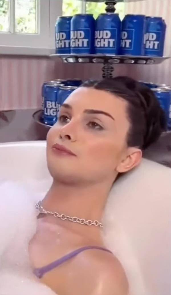 Dylan Mulvaney in the bath with Bud Light cans in the back.