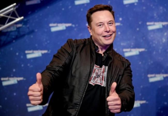 Elon Musk poses with both thumbs up.